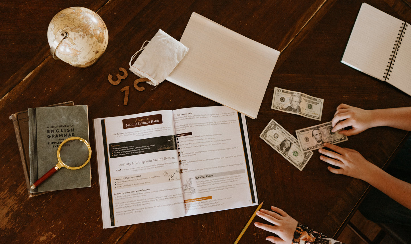 Child counting money on a desk with educational materials and a globe.
